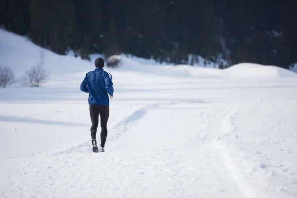 Muž jogging na sněhu v lese — Stock fotografie