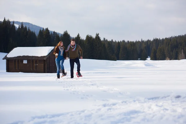 Casal se divertindo em sapatos de neve — Fotografia de Stock