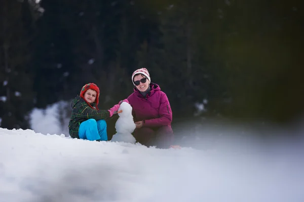 Mãe e filho construindo boneco de neve — Fotografia de Stock