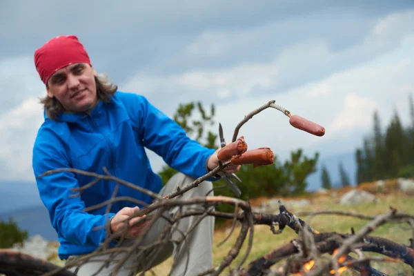 Hiking adam kamp ateşi üzerinde lezzetli sosis hazırlamak — Stok fotoğraf