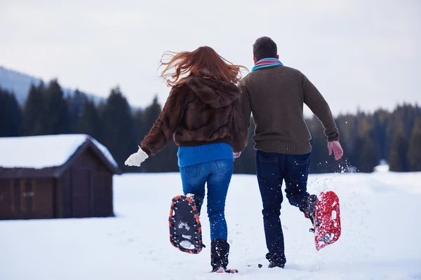 Casal se divertindo em sapatos de neve — Fotografia de Stock