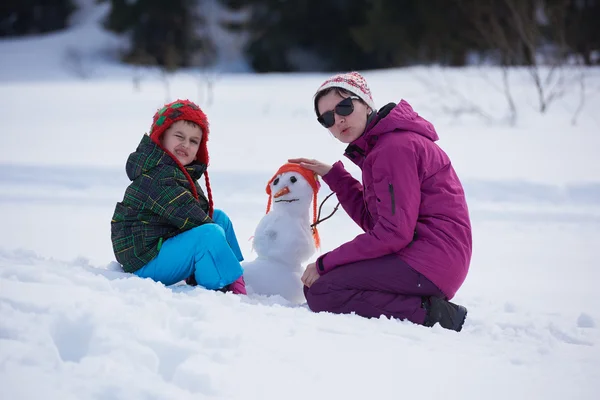 Anne ve oğlu kardan adam bina — Stok fotoğraf