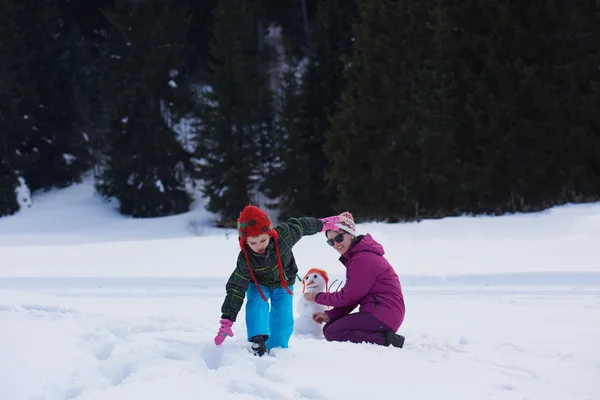 Madre e hijo construyendo muñeco de nieve —  Fotos de Stock