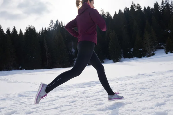 Jeune femme jogging en plein air sur la neige dans la forêt — Photo