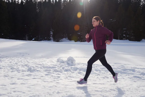 Young woman jogging outdoor on snow in forest — Stock Photo, Image