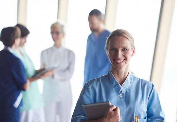 Female doctor with tablet computer  standing in front of team — Stock Photo, Image