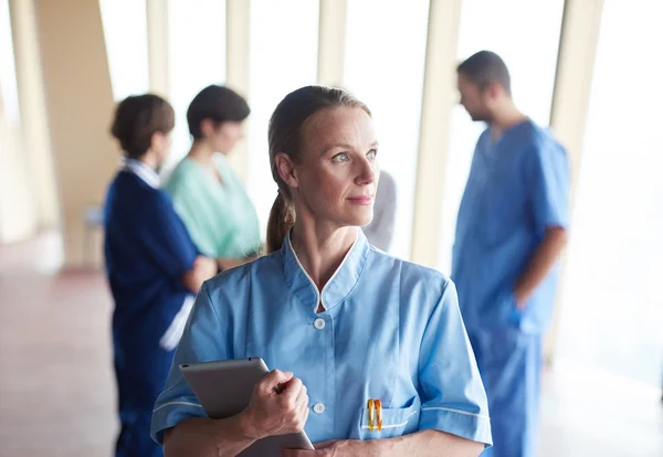 Medico donna con tablet in piedi davanti al team — Foto Stock