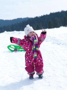 little baby girl having fun on fresh snow clipart