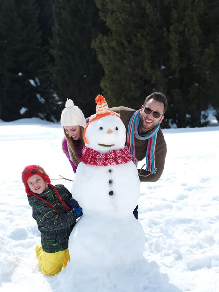 Gelukkige familie sneeuwpop maken — Stockfoto