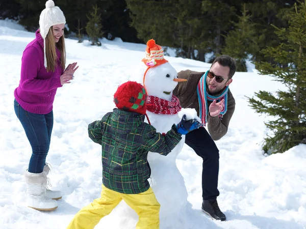 Gelukkige familie sneeuwpop maken — Stockfoto