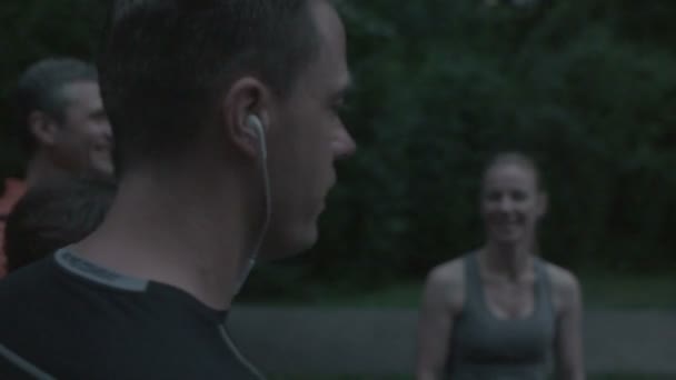 Groep vrienden doen pauze na joggen in het park — Stockvideo