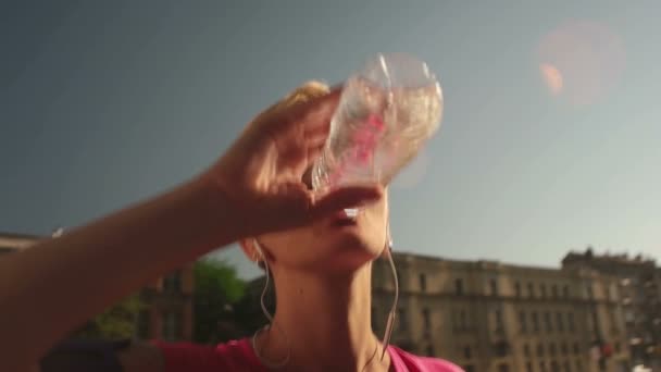 Молодая женщина пьет воду после пробежки — стоковое видео