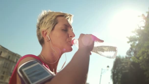Jonge vrouw drinken een water na het joggen — Stockvideo