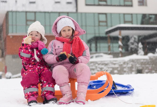 Birlikte kızakları üzerinde oturan iki küçük grils portresi — Stok fotoğraf