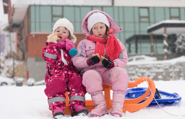 Portrait of two little grils sitting together on sledges — Stock Photo, Image