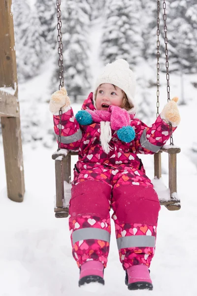 Liten flicka på snöig vinterdag swing i park — Stockfoto