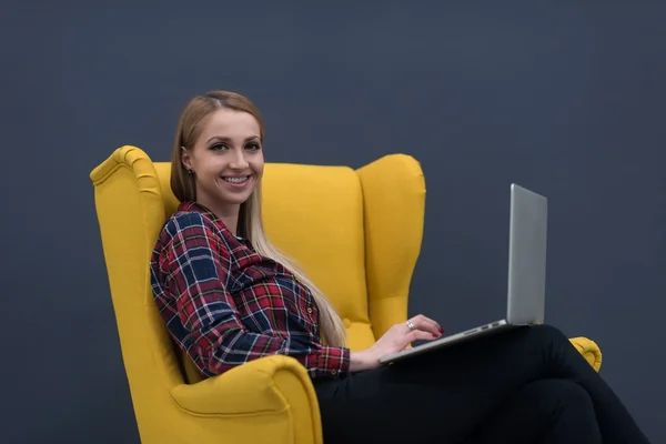 Вверх по бизнесу, женщина работает на ноутбуке и сидит на желтом — стоковое фото