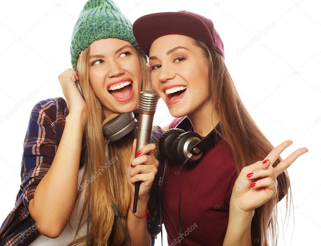 two beauty hipster girls with a microphone singing and having f