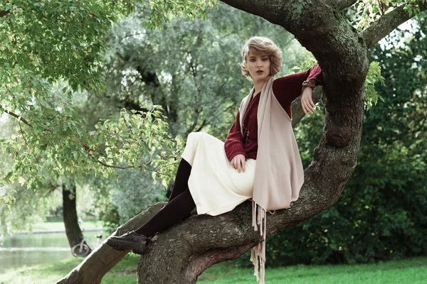 Όμορφη κοπέλα ποζάρει σε ένα δέντρο. — Φωτογραφία Αρχείου