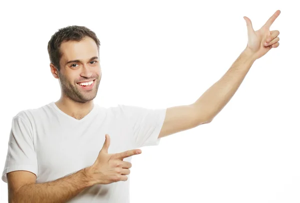 Young smiling happy man shows something — Stock Photo, Image