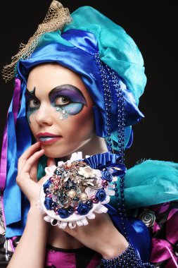 Yaratıcı makyajlı bir kadın bir buket mücevher tutuyor.