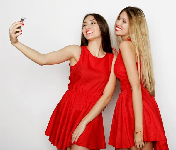 Due giovani donne che indossano un vestito rosso scattando selfie — Foto Stock