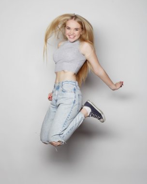 Gülümseyen genç kadın havada zıplıyor.