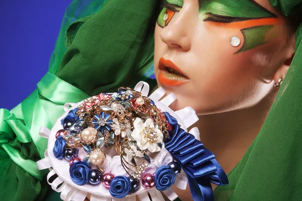 Γυναίκα με δημιουργικό μακιγιάζ κρατώντας ένα μπουκέτο κοσμήματα — Φωτογραφία Αρχείου
