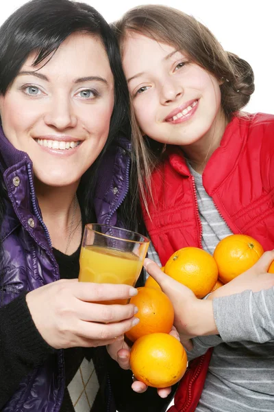 Barn med mor anläggning apelsiner och juice — Stockfoto