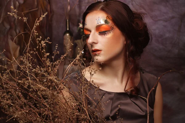 Mujer con maquillaje brillante con ramas secas — Foto de Stock