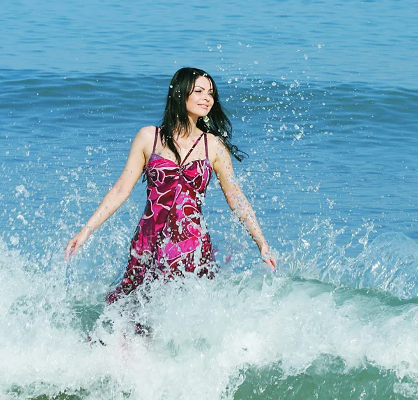 Joven mujer sonriente de pie en olas marinas —  Fotos de Stock