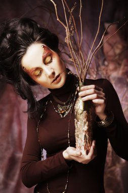 Kuru dallarla süslenmiş parlak bir kadın.