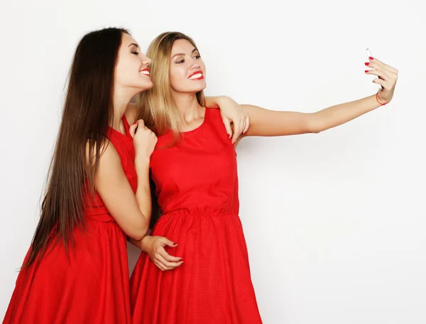 Twee jonge vrouwen dragen rode jurk nemen selfie — Stockfoto