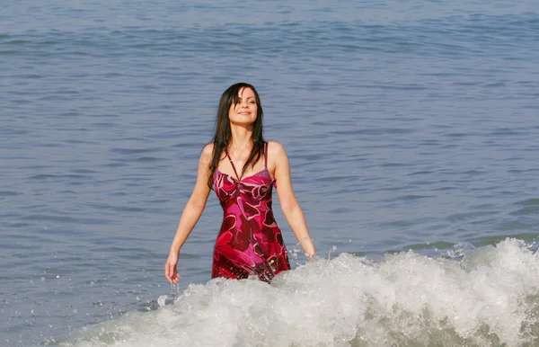 Μικρά χαμογελαστή γυναίκα να στέκεται στα κύματα της θάλασσας — Φωτογραφία Αρχείου