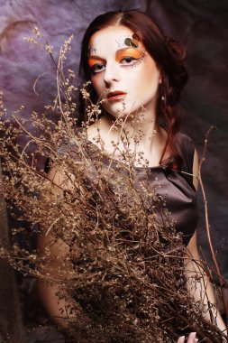 Kuru dallarla süslenmiş parlak bir kadın.