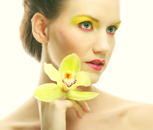 Mladá žena s světlý make-up drží orchidej — Stock fotografie