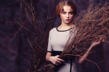 Kuru dallarla süslenmiş parlak bir kadın.