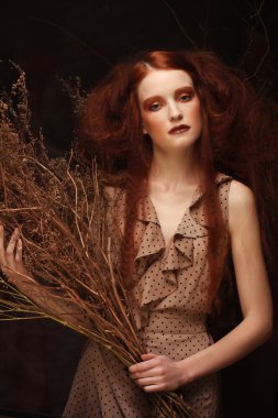 Kuru dallarla süslenmiş parlak bir kadın.