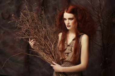 Kuru dallarla süslenmiş parlak bir kadın.