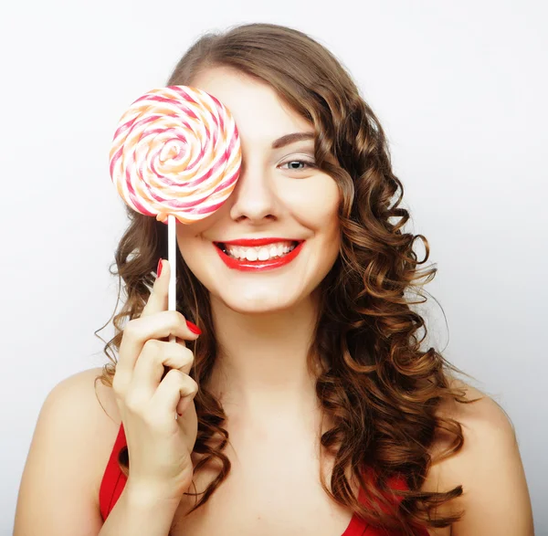 Smiling cute girl covering her eye with lollipop over white back — Stock Photo, Image