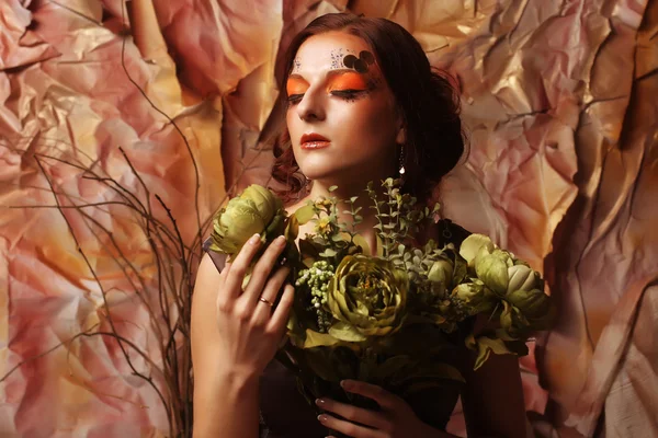 Woman with bright creative make up holding green flowers — Stock Photo, Image