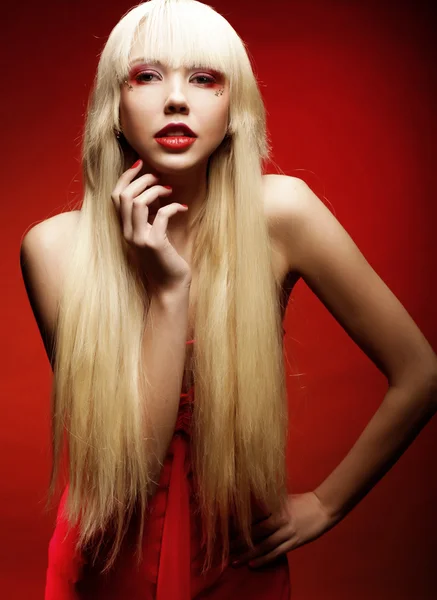 Perfekta blond modell i röd klänning över röd bakgrund. — Stockfoto