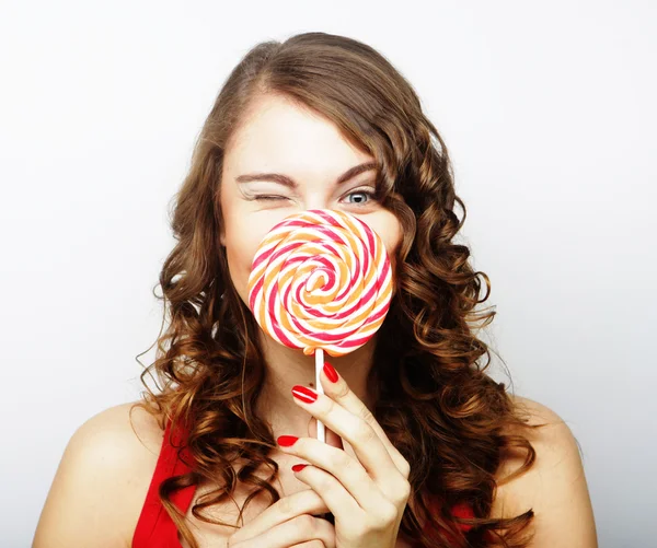 Portrait of a smiling cute girl covering her lips with lollipop — Stock Photo, Image