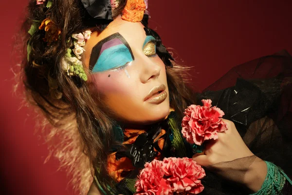 Vrouw met creatieve make-up houden roze bloem — Stockfoto