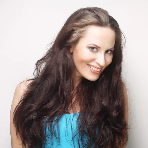 Smiling brunette woman over grey background — Stock Photo, Image