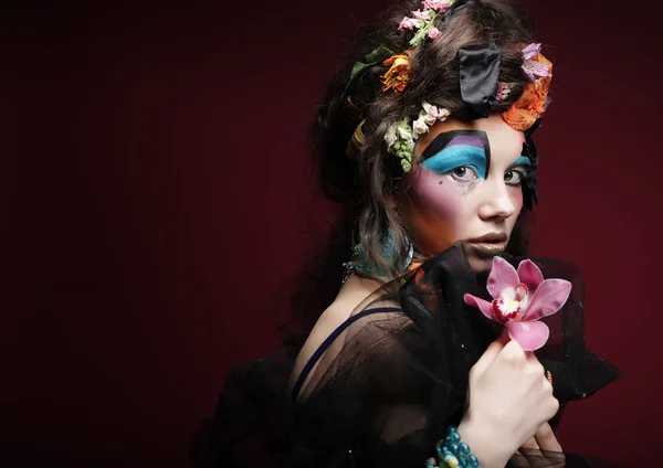 Woman with creative make up holding pink flower — Stock Photo, Image