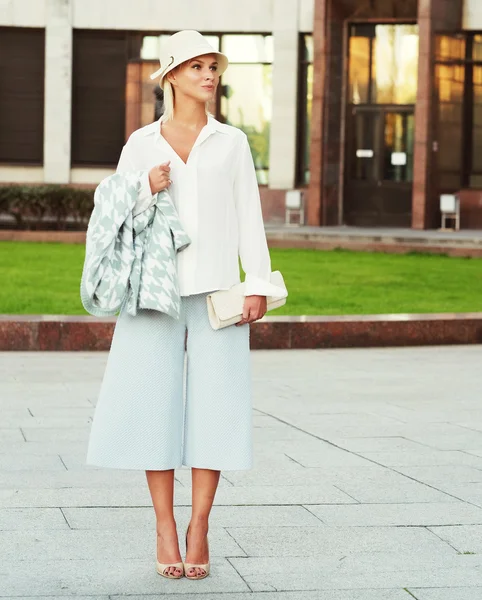 Jeune femme blonde marchant dans la rue — Photo