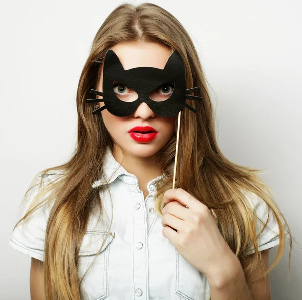 Giovane donna giocherellona con una maschera da festa — Foto Stock