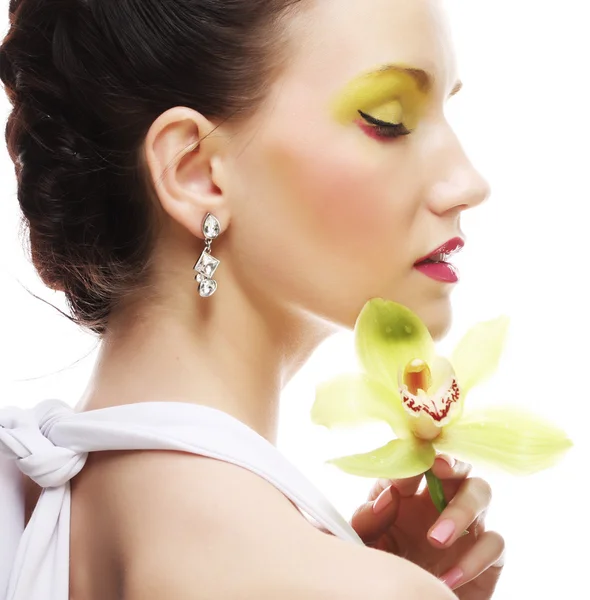 Joven mujer con brillante maquillaje celebración orquídea —  Fotos de Stock