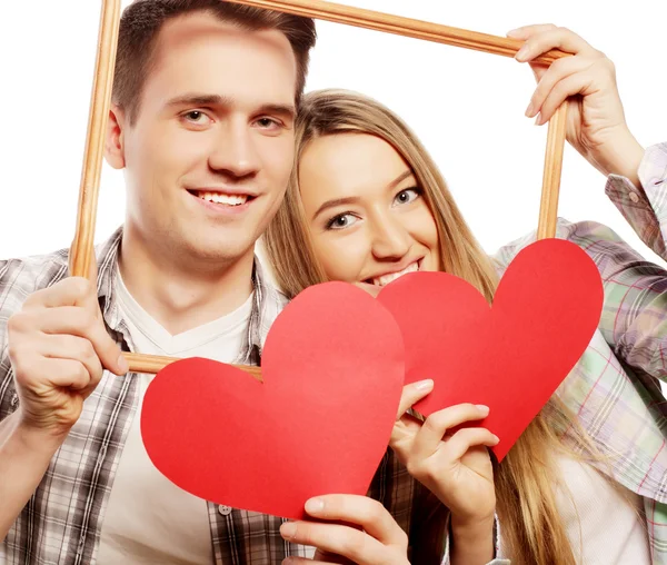 Encantador casal segurando quadro e corações vermelhos — Fotografia de Stock